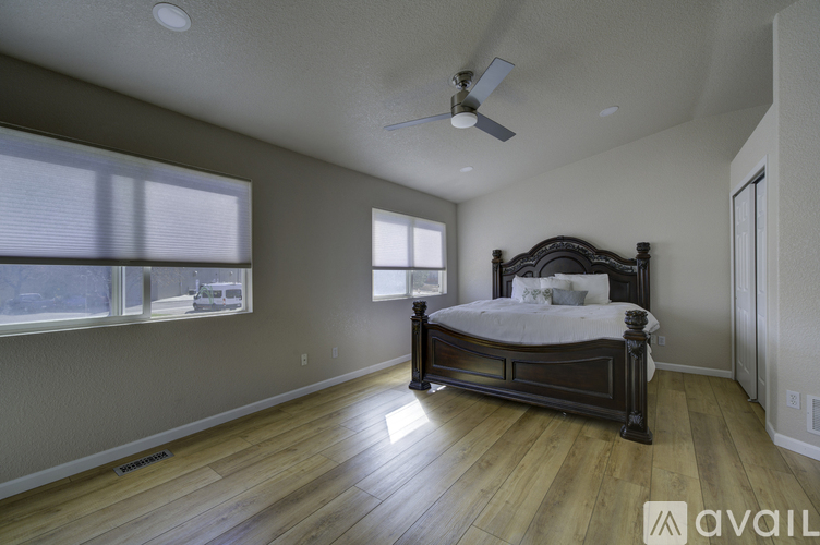 A bedroom with a large bed and a ceiling fan.