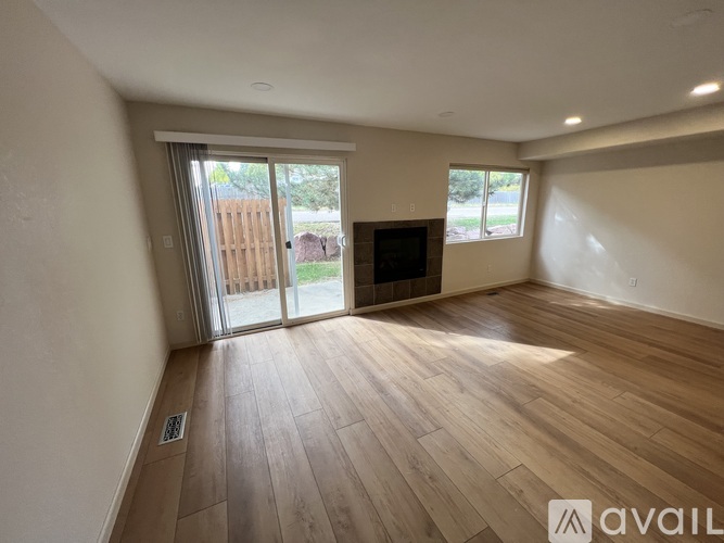 A spacious room with wooden flooring and a sliding glass door leading outside.