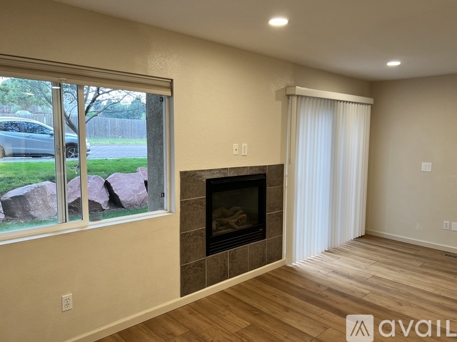 A living room with a fireplace and a window overlooking a yard.
