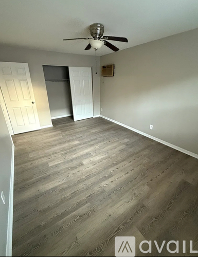 A room with a ceiling fan and wooden flooring.