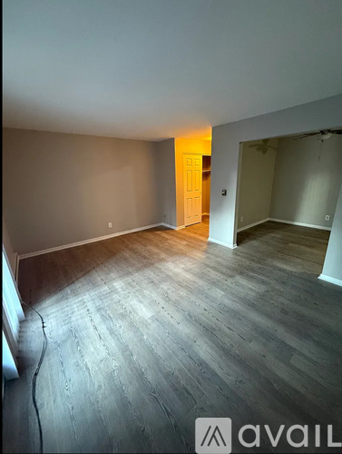 A room with wooden flooring and a doorway leading to another room.