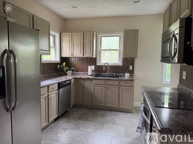 A kitchen with a refrigerator on the left and a sink in the middle.
