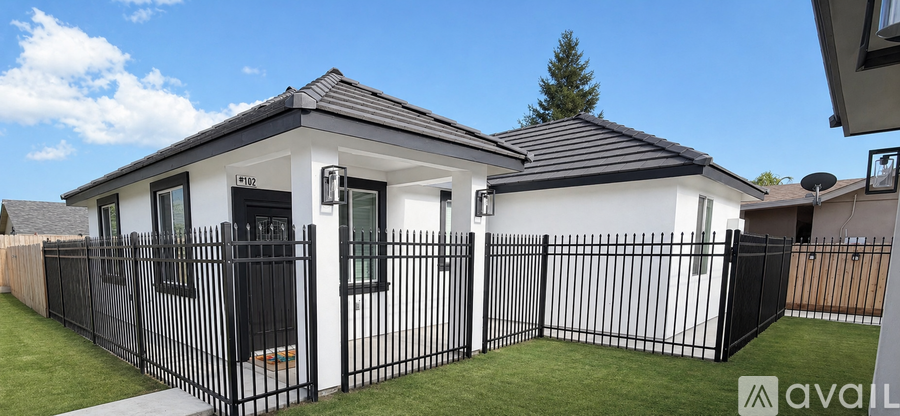 A small white house with a black fence in front.