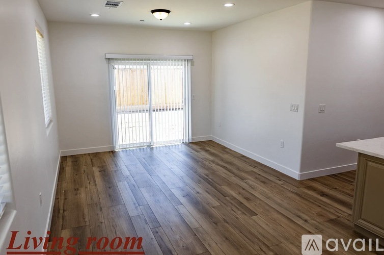 A living room with wooden flooring and a window with blinds.