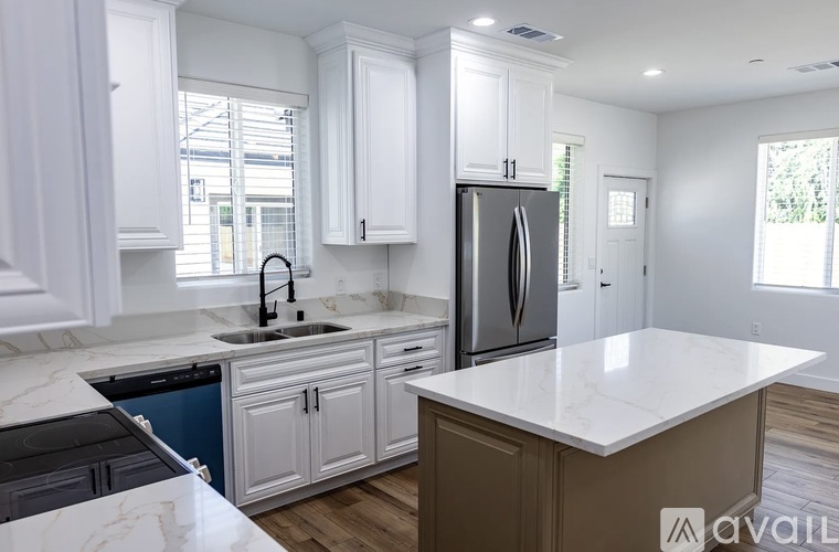 A kitchen with white cabinets and a marble countertop.