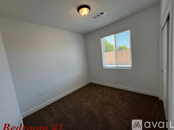 A bedroom with a window and a carpeted floor.
