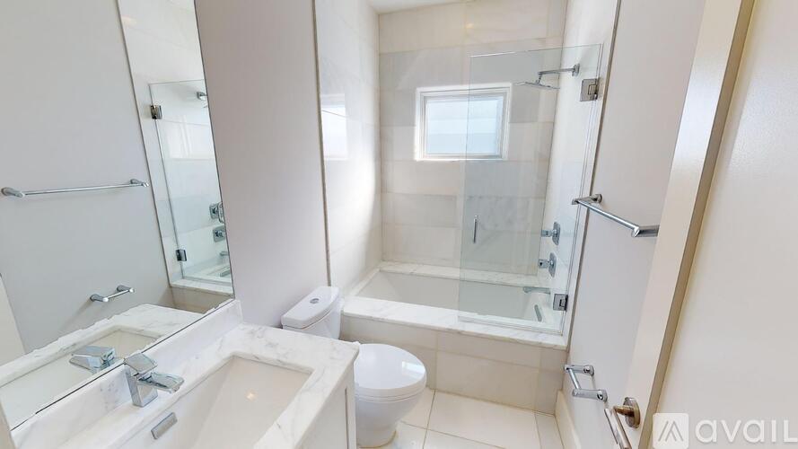 A white bathroom with a glass shower stall and a toilet.