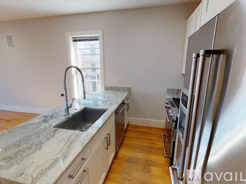 A kitchen with a marble countertop and stainless steel appliances.