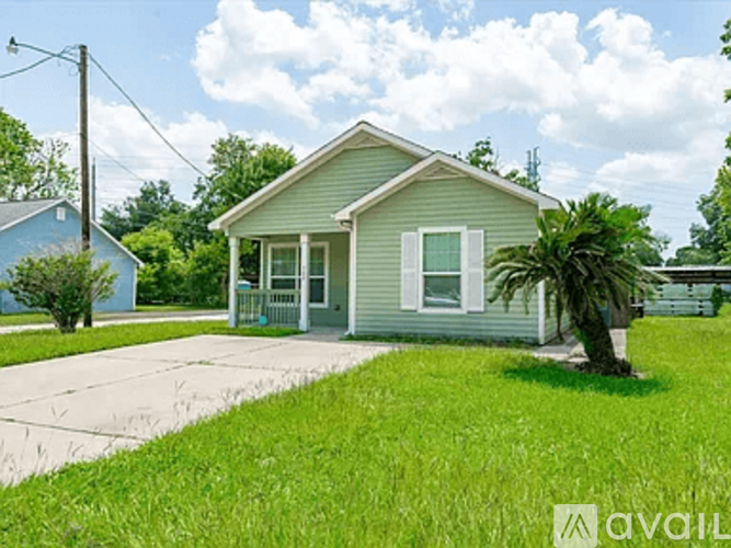 A house with a green lawn and a palm tree in front.