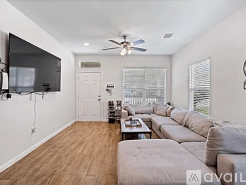 A living room with a grey couch and a flat screen TV mounted on the wall.