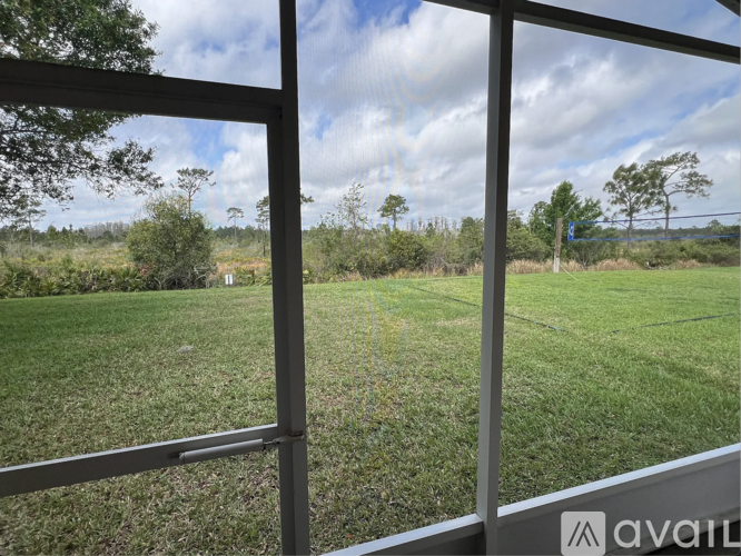 A view from a window looking out to a field with trees.