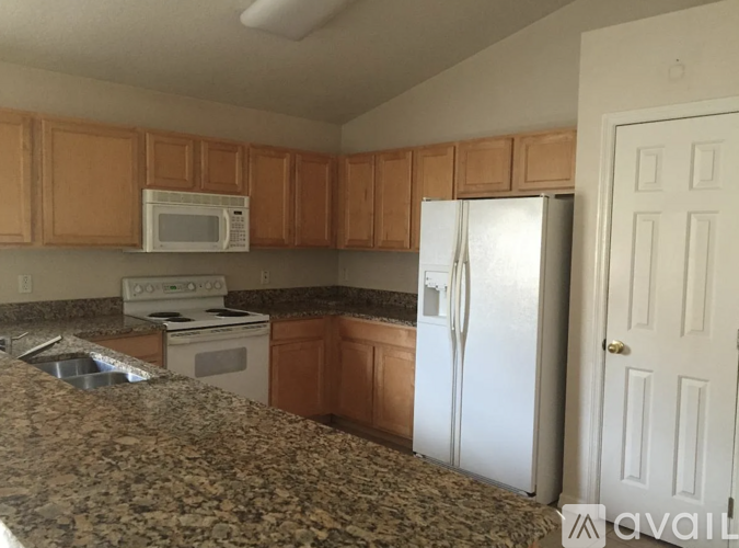 A kitchen with brown cabinets and a granite countertop.