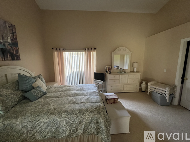 A bedroom with a large bed, a dresser, and a window with curtains.