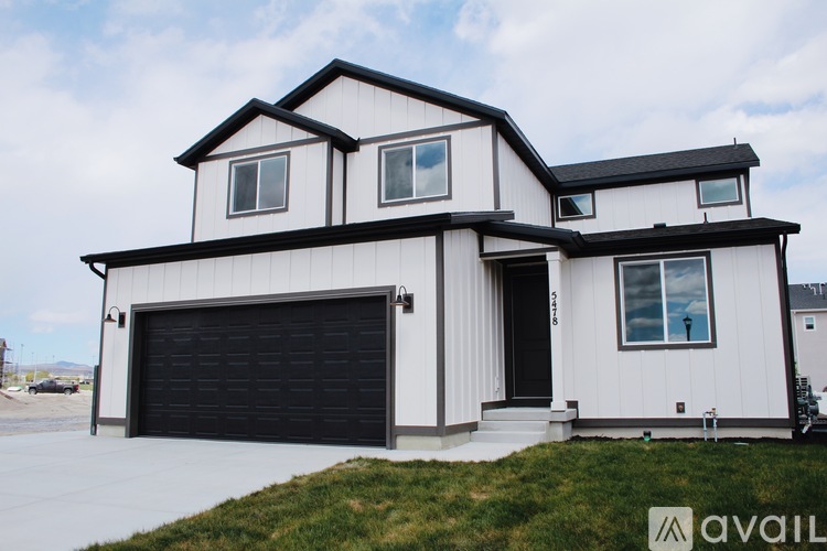 A modern house with a black garage door is for sale.