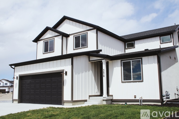 A white house with a black garage door is for sale.