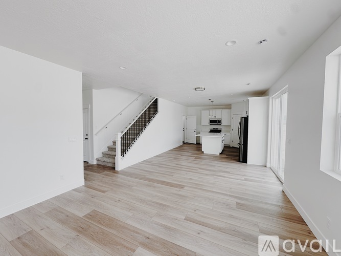 A spacious room with wooden flooring and a staircase.