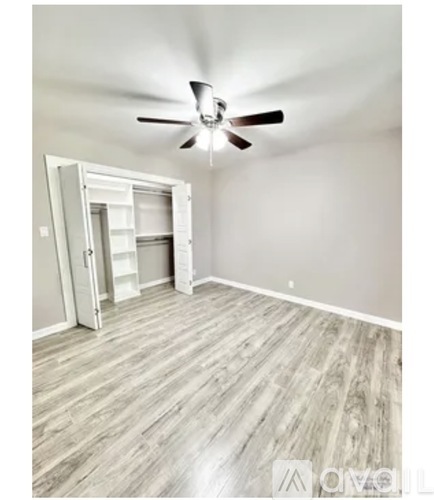 A room with a ceiling fan and a doorway leading to another room.