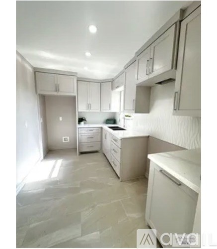 A kitchen with white cabinets and a stone floor.