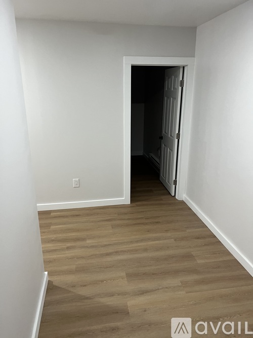 A room with a wooden floor and a doorway leading to another room.