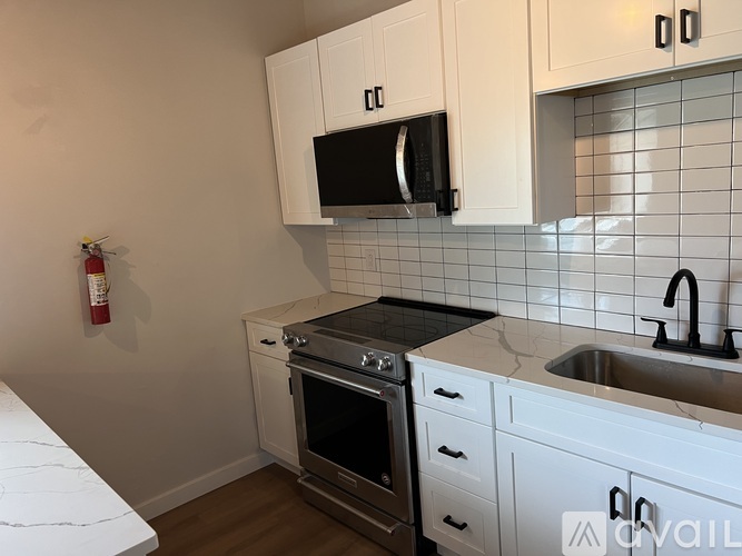 A kitchen with white cabinets and a black microwave.