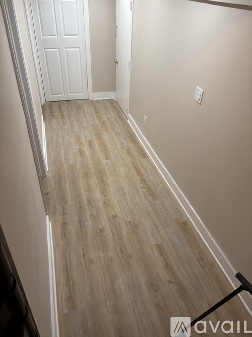 A hallway with wooden flooring and a white door.