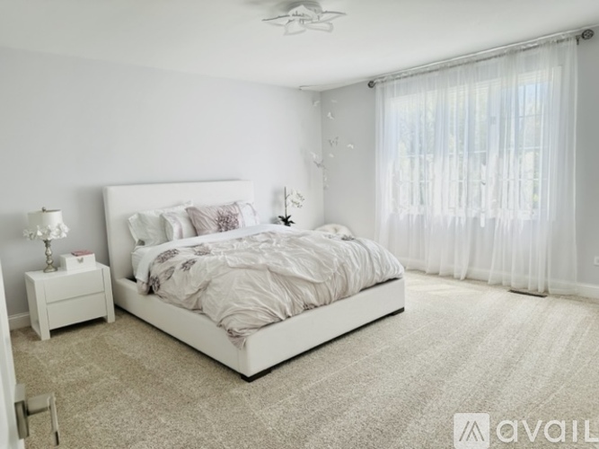 A bedroom with a large bed and a window with curtains.