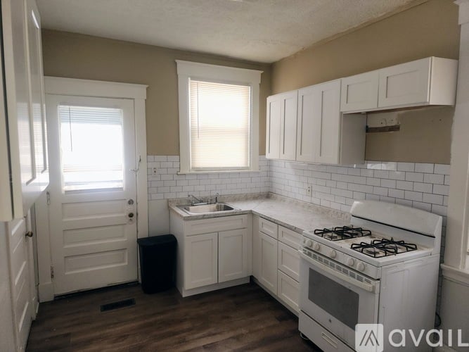 A kitchen with white cabinets and a white stove top oven.
