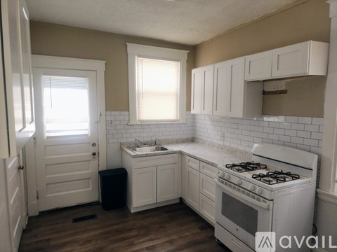 A kitchen with white cabinets and a white stove top oven.
