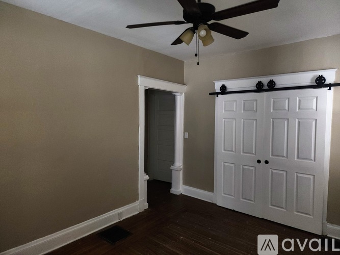 A room with a ceiling fan and a white door.