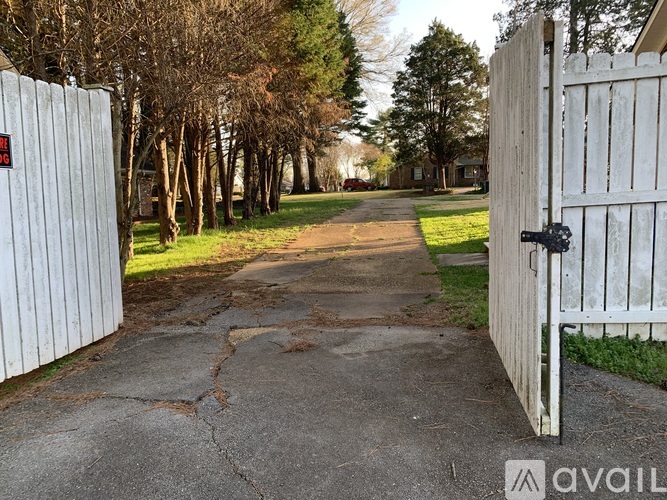 A white gate blocks the entrance to a driveway.