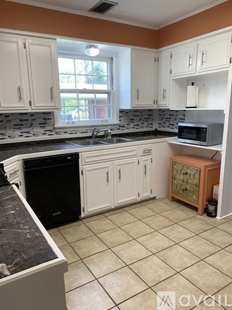 A kitchen with white cabinets and a black dishwasher.