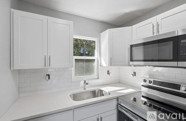 A kitchen with white cabinets and a black microwave.