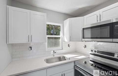 A kitchen with white cabinets and a black microwave.