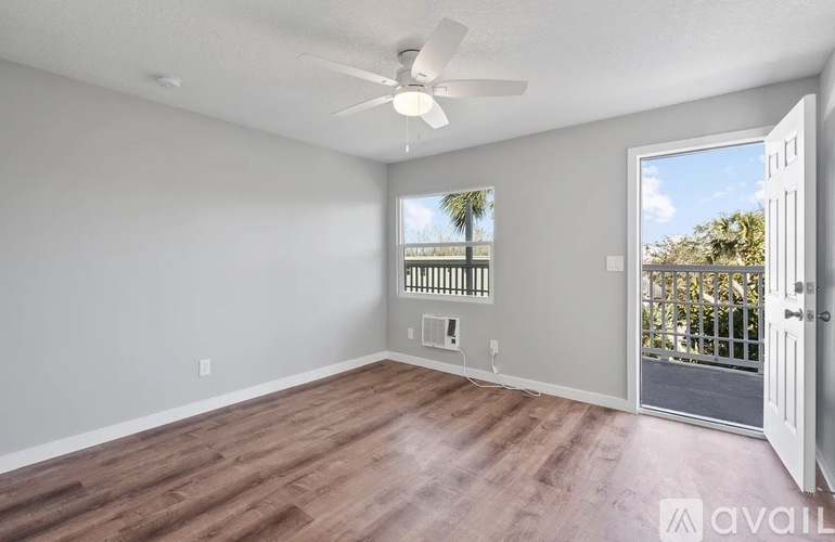A room with a ceiling fan and a view of a balcony with a railing.