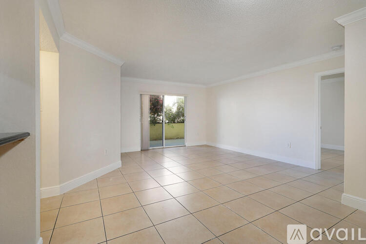 A spacious room with tiled flooring and a sliding glass door leading to a balcony.
