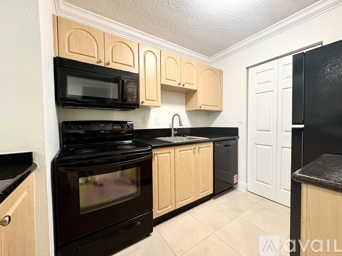 A kitchen with black appliances and wooden cabinets.
