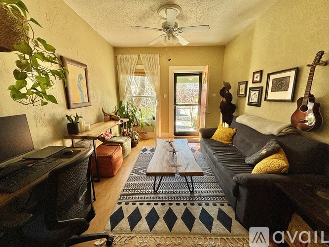 A living room with a couch, a coffee table, a television, and a guitar hanging on the wall.