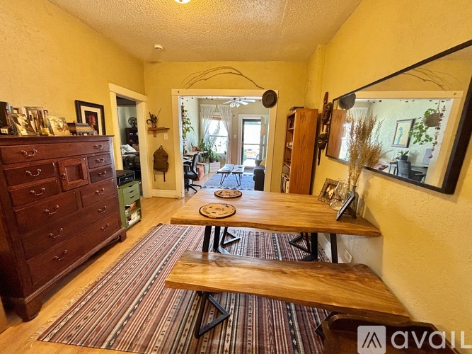A room with a wooden table and bench in the middle of a striped rug.