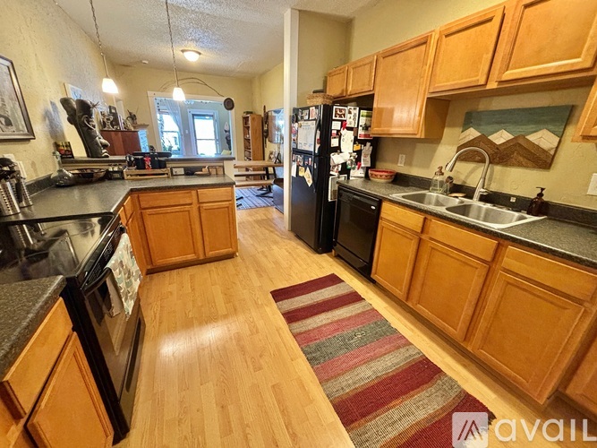 A kitchen with wooden cabinets and a black fridge.