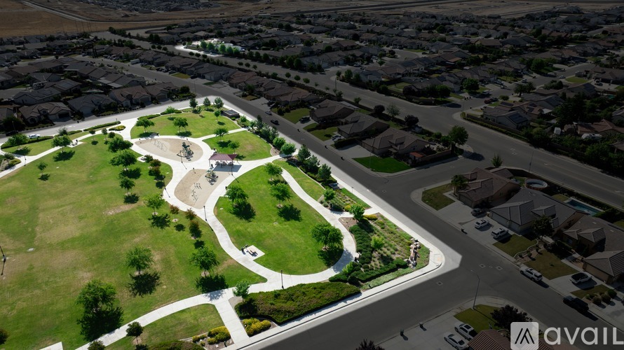 A bird's eye view of a neighborhood with a large green space and a road curving around it.