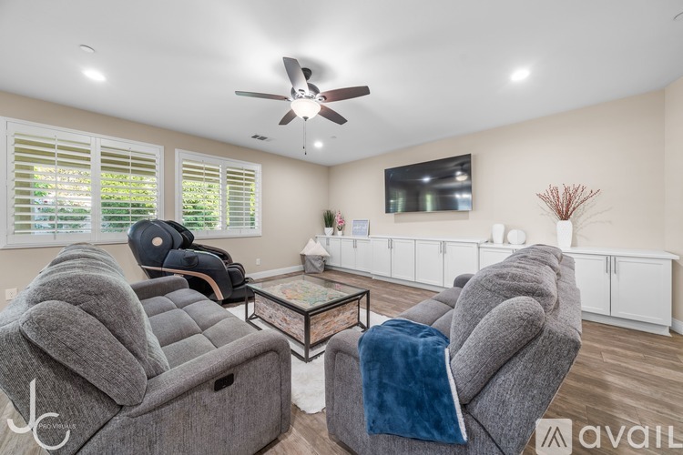A living room with grey couches and a ceiling fan.