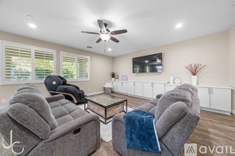 A living room with grey couches and a ceiling fan.