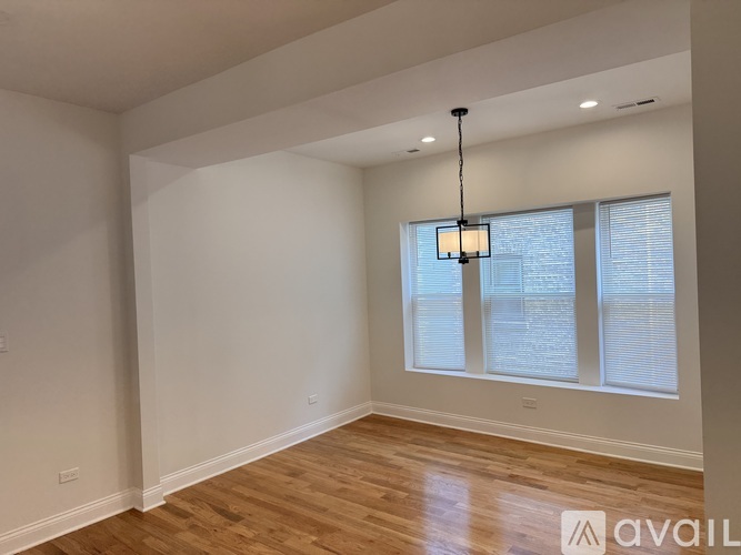A room with wooden floors and a window with blinds.