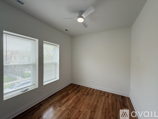 A room with a ceiling fan and two windows with blinds.