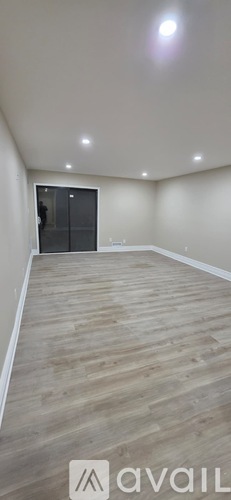 A room with wooden flooring and a sliding glass door.