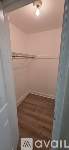 A small, empty room with wooden flooring and a white door.