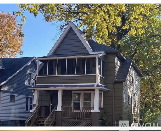 A house with a porch and a tree in the background.