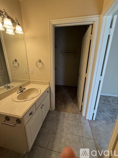 A bathroom with a sink, mirror, and a door leading to another room.