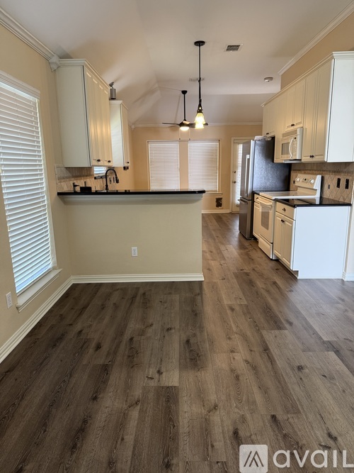 A kitchen with wooden floors and white cabinets.