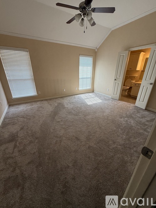 A room with a carpeted floor and a ceiling fan.